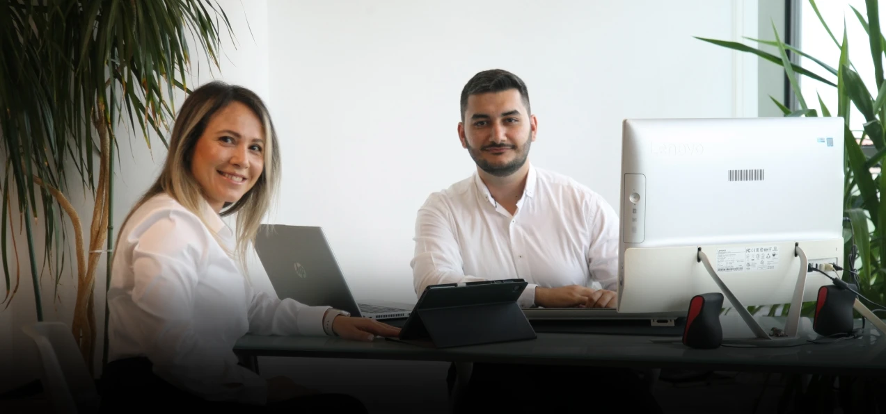 Roxana and Alin standing at a desk looking at the camera